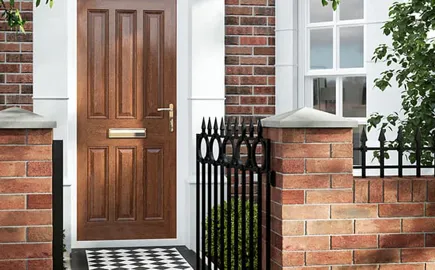 Wooden front door with black metal gate and brick wall