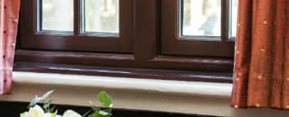 Close up of a gold modern handle on a brown Everest casement window