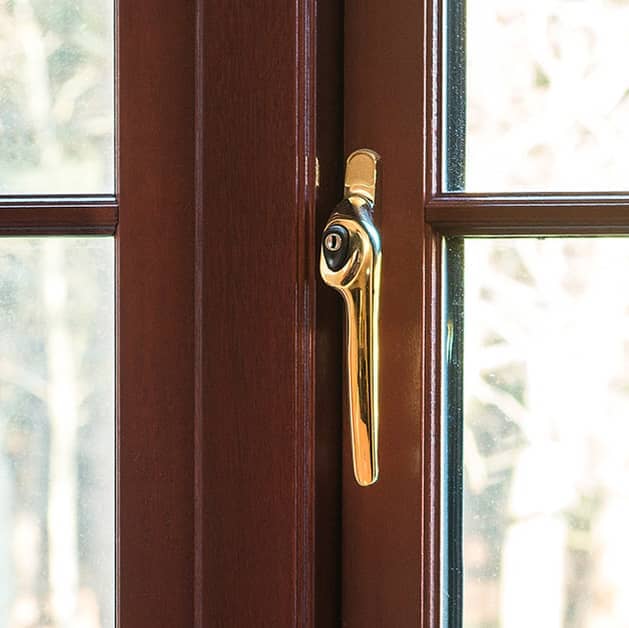 Close up of a gold modern handle on a brown Everest casement window