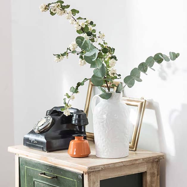 White vase with white flowers on a table