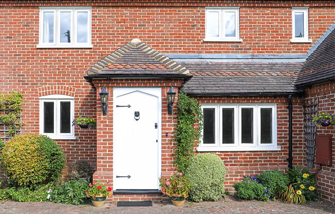 A brick home with white uPVC windows and matching white front door