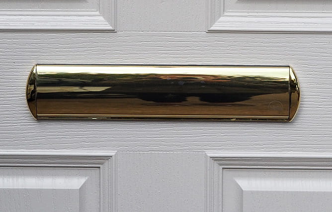 A close up view of a gold letterbox on an Everest composite door