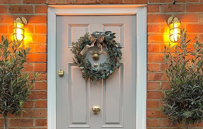 A composite entrance door on a brick house with lights