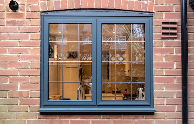 A black aluminium slim frame window with leaded glass