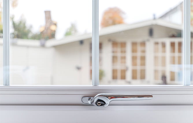 A white uPVC triple glazed window with Georgian bars and a chrome window handle