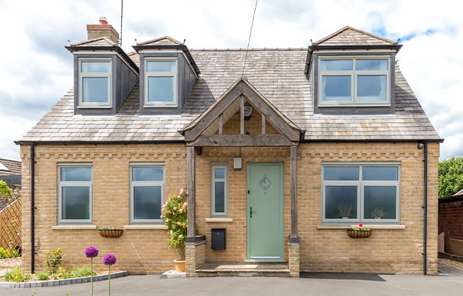 A beautiful home with Anthracite grey windows and a chartwell green composite front door