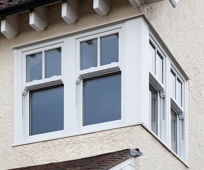 A uPVC white sash corner window seen on an old property