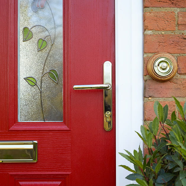 Close up of a red composite door with glazing panels