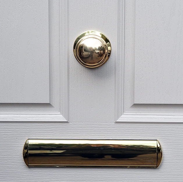 Gold letterbox and door knob on a grey door