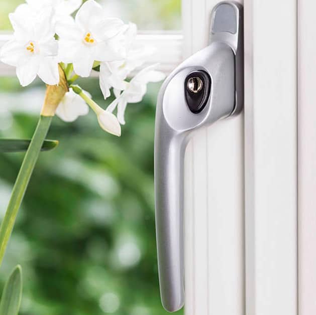 An Everest chrome standard handle on white uPVC Everest window with flower