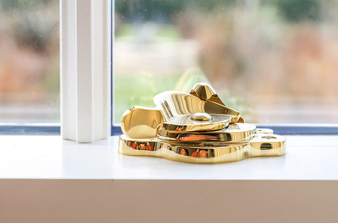 Gold window latch on white windowsill