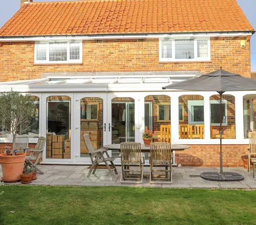 White Everest conservatory with patio furniture and garden