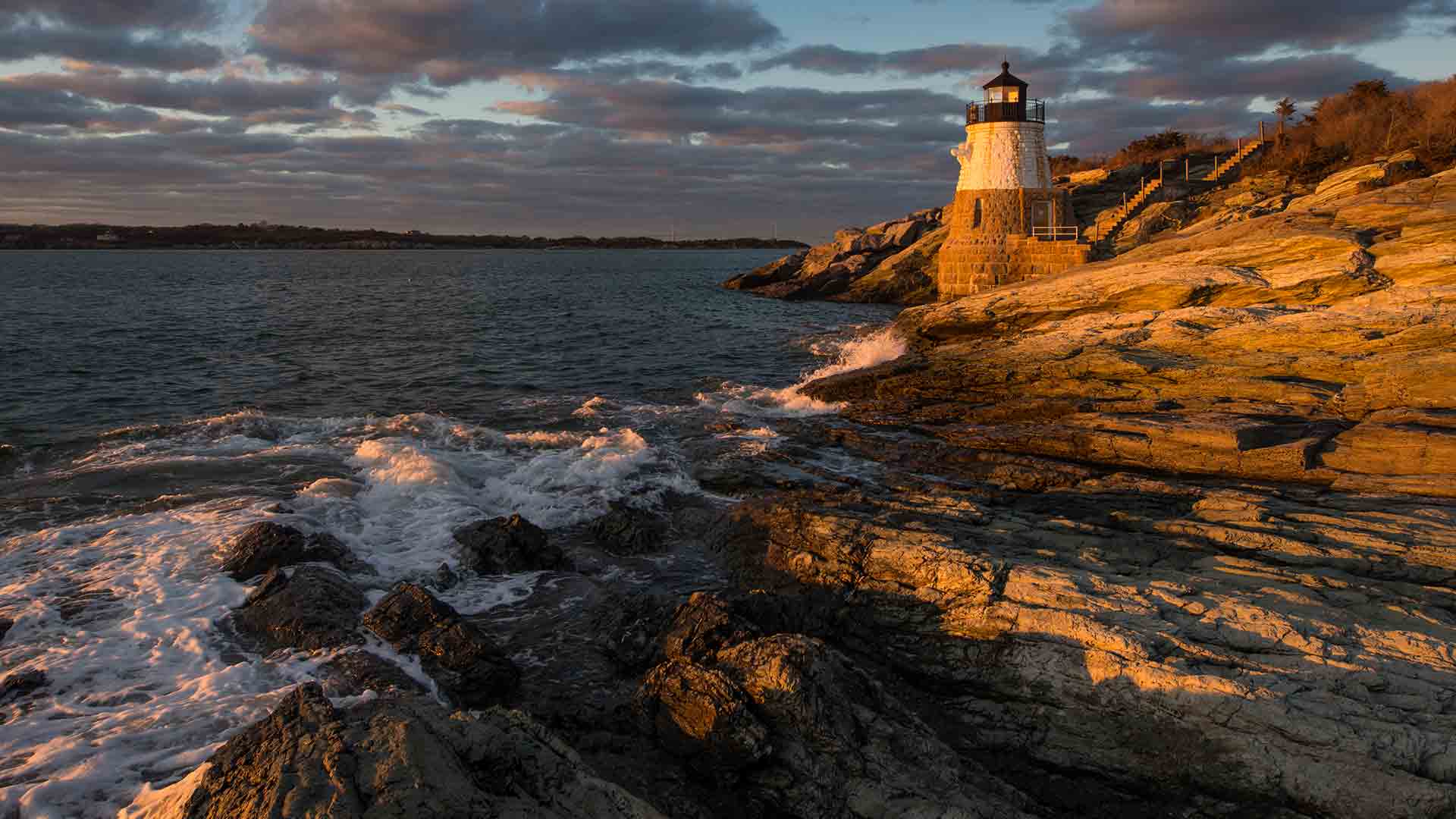 Lighthouse on rocky coast at sunset