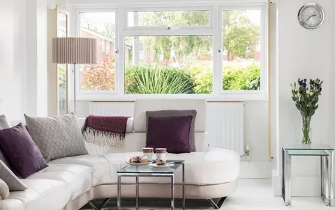 White leather sofa with purple cushions and a glass coffee table