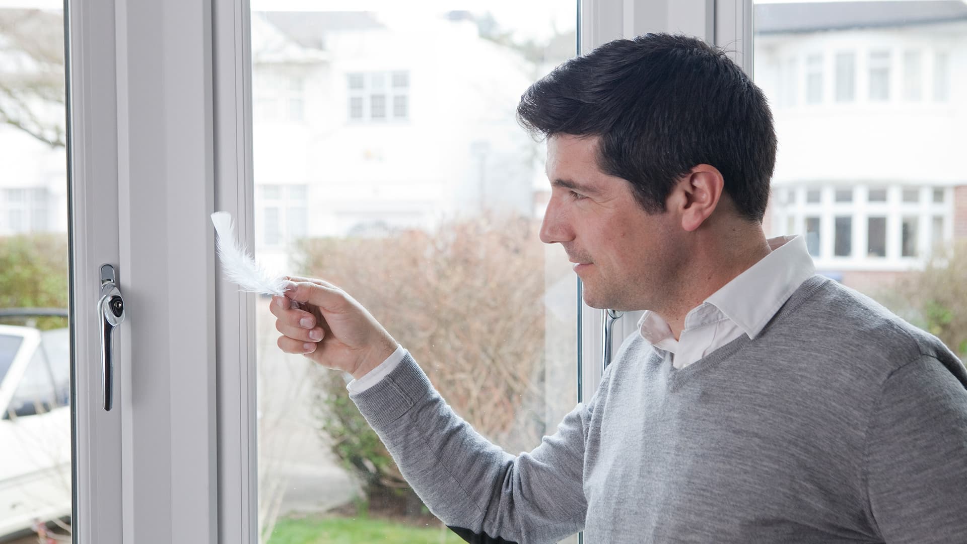 Man checking Everest conservatory window tightness with feather