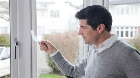 Man checking Everest conservatory window tightness with feather