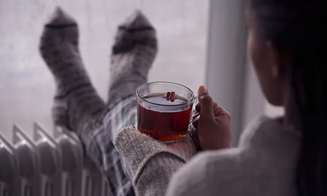 Person holding a cup of tea with cinnamon sticks
