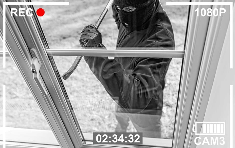 Person in dark clothing using crowbar to break window