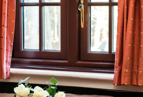 Dark red Everest conservatory window with white sill and flowers