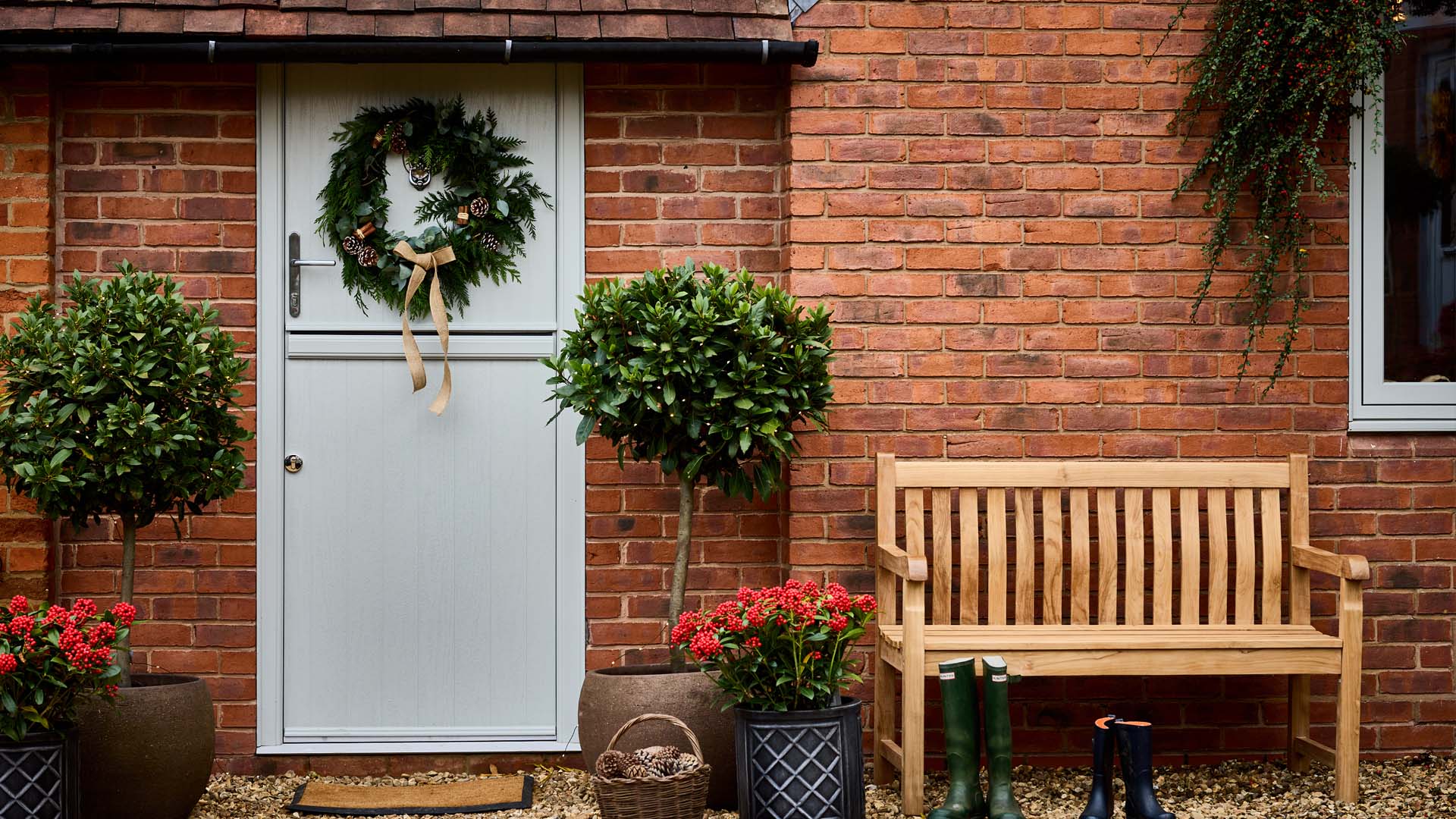 Christmas decorations on light grey door with potted plants