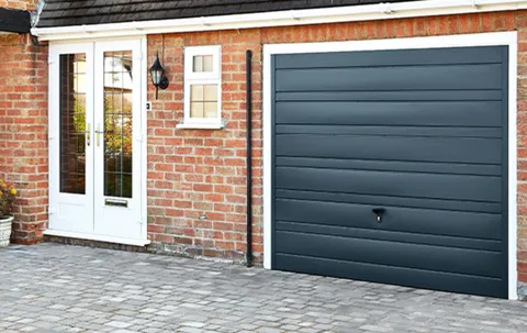 Dark grey garage door on brick house