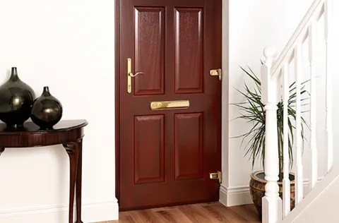 Red wooden door with brass hardware in hallway