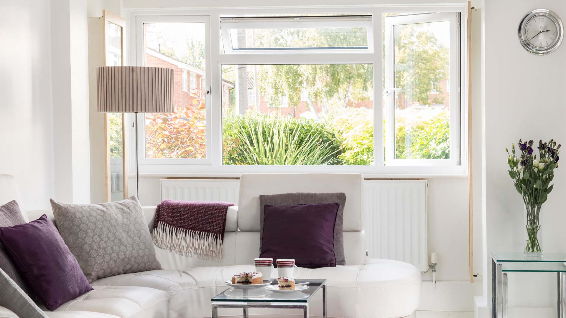 White living room with purple cushions and window view