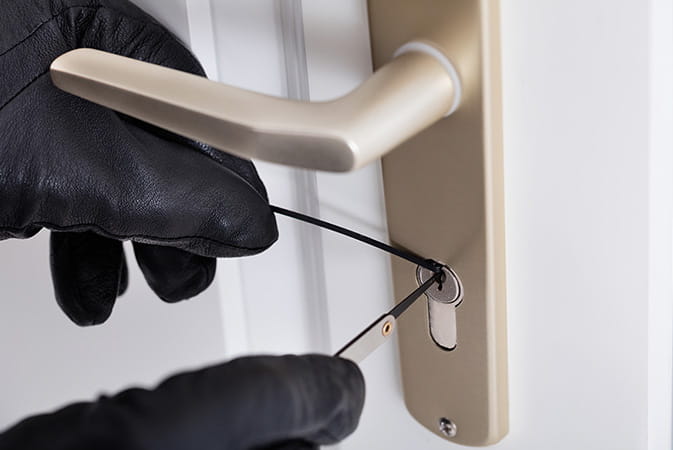Black gloves picking lock with tools