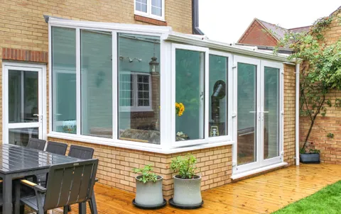 White Everest conservatory with brickwork and patio area