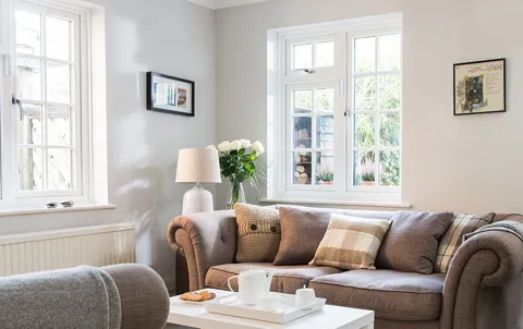Light brown sofa with white pillows and window