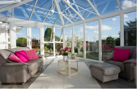 Everest conservatory with gray sofa, pink cushions, and white furniture