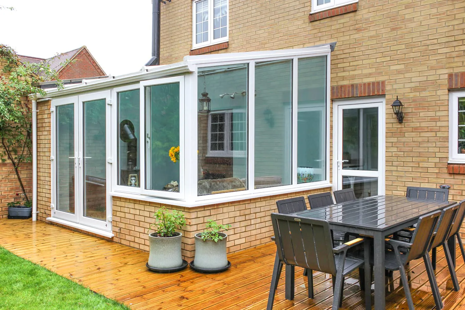 White Everest conservatory with a wooden deck and black patio furniture