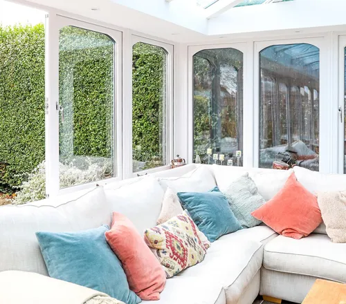Everest conservatory with white windows and cream sofa with colorful cushions