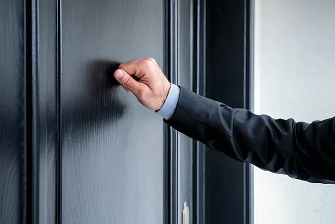 Hand knocking on black door