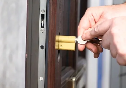 Hands inserting key into a dark brown door lock