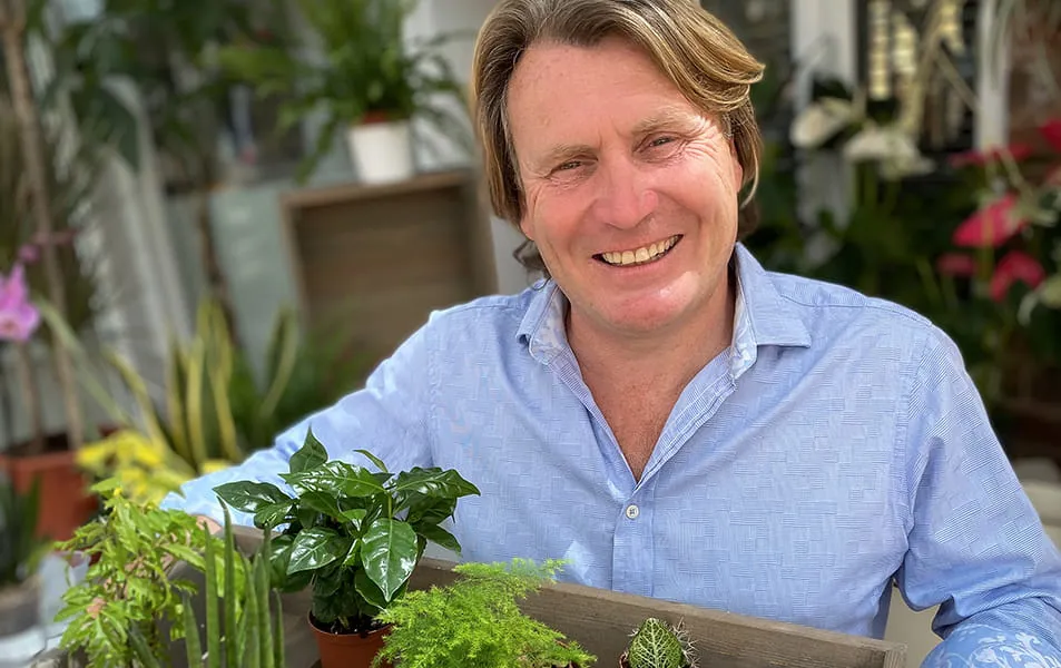 Man smiling holding small potted plants
