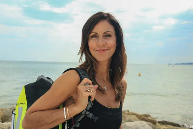 Woman smiling at the beach with a backpack