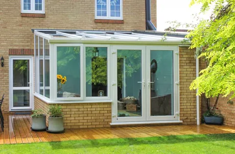 White Everest conservatory with brickwork and wooden decking