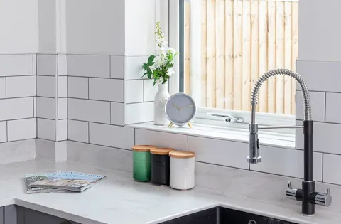 White brick tiles kitchen window with tap and clock