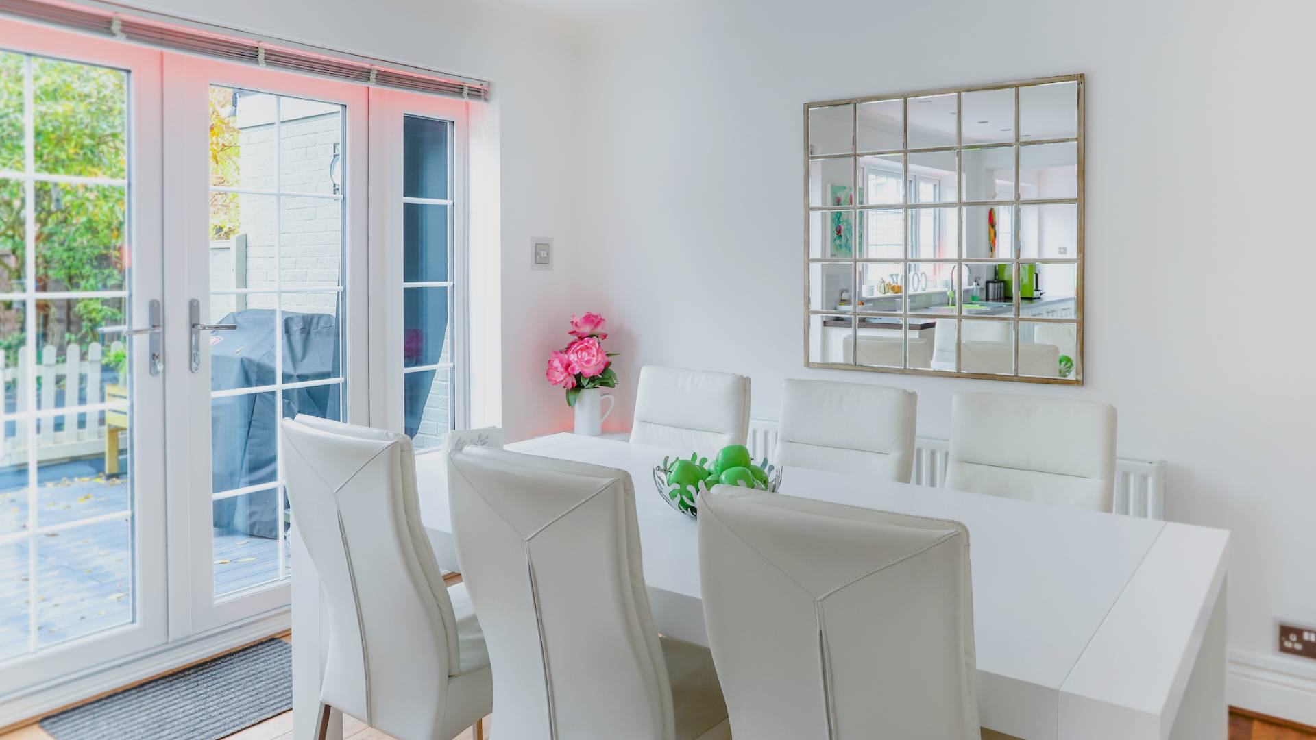White dining table with white chairs and pink flowers