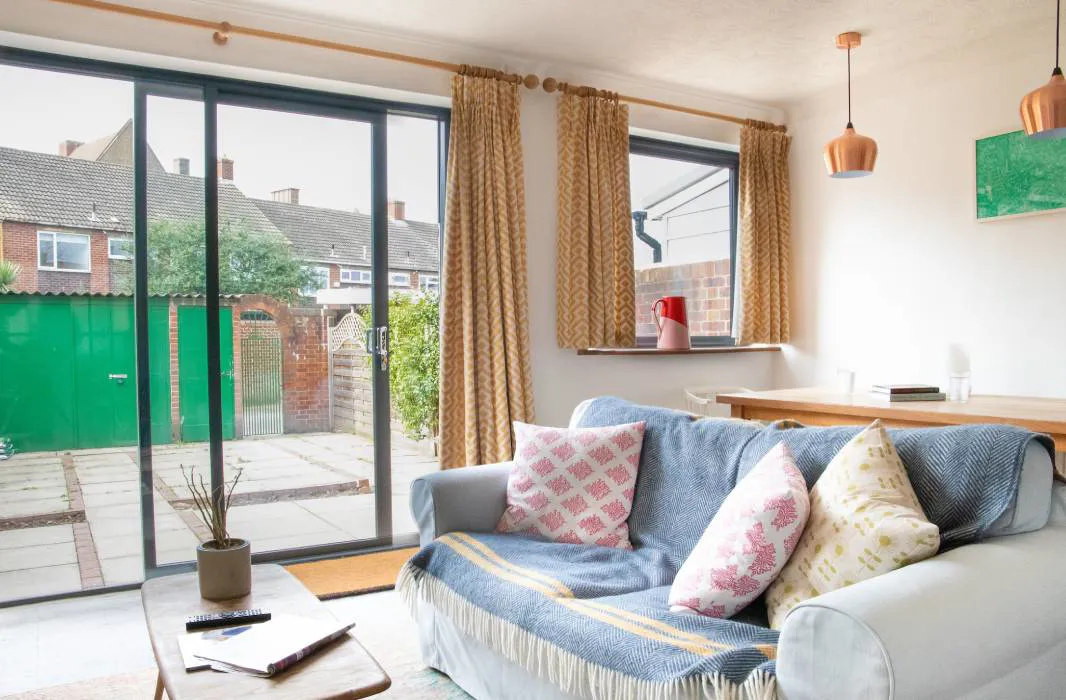 Everest conservatory with light gray couch, patterned pillows, and yellow/gold curtains