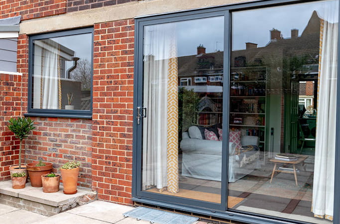 Grey Everest conservatory sliding doors with brick wall