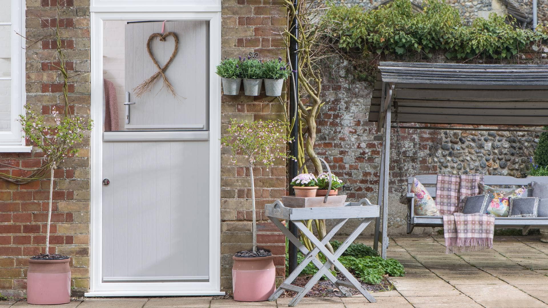 Grey painted door with heart wreath and potted plants