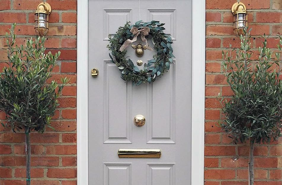 Light gray door with gold wreath and plants