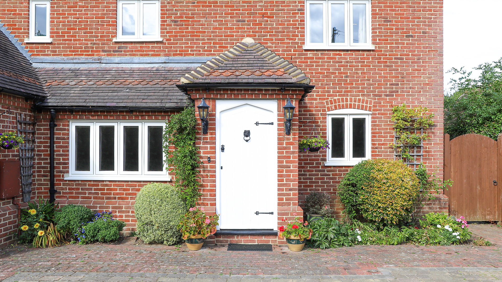 White door with brick house and flowers