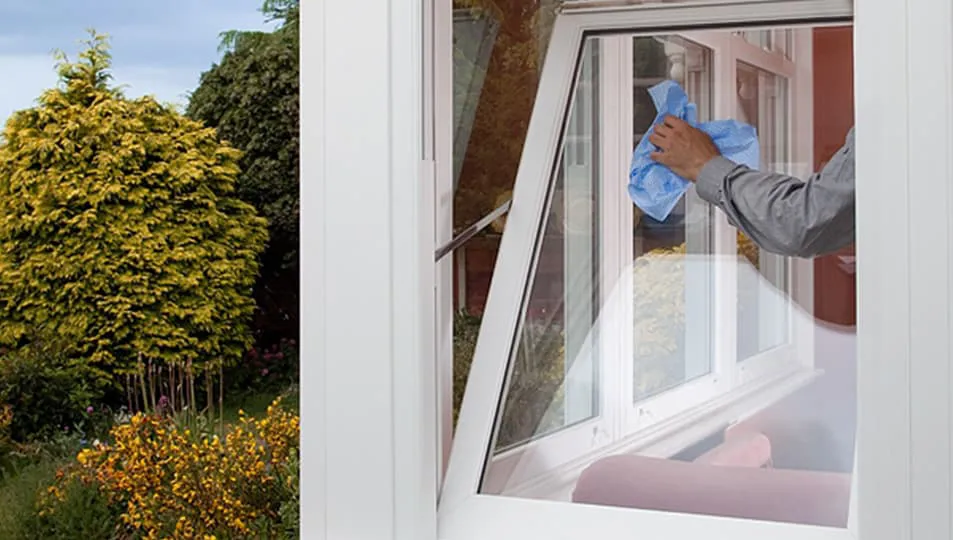 Person cleaning Everest conservatory window with blue cloth