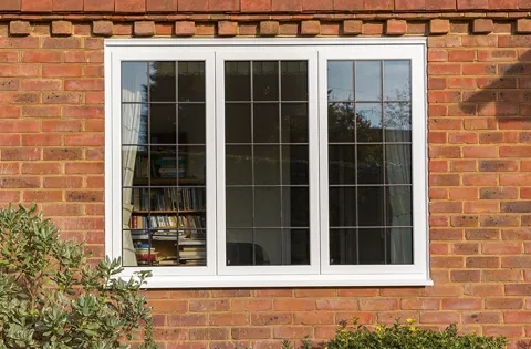 White window with leaded glass on brick wall