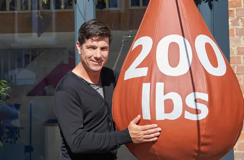 Man holding large 200 lbs terracotta weight