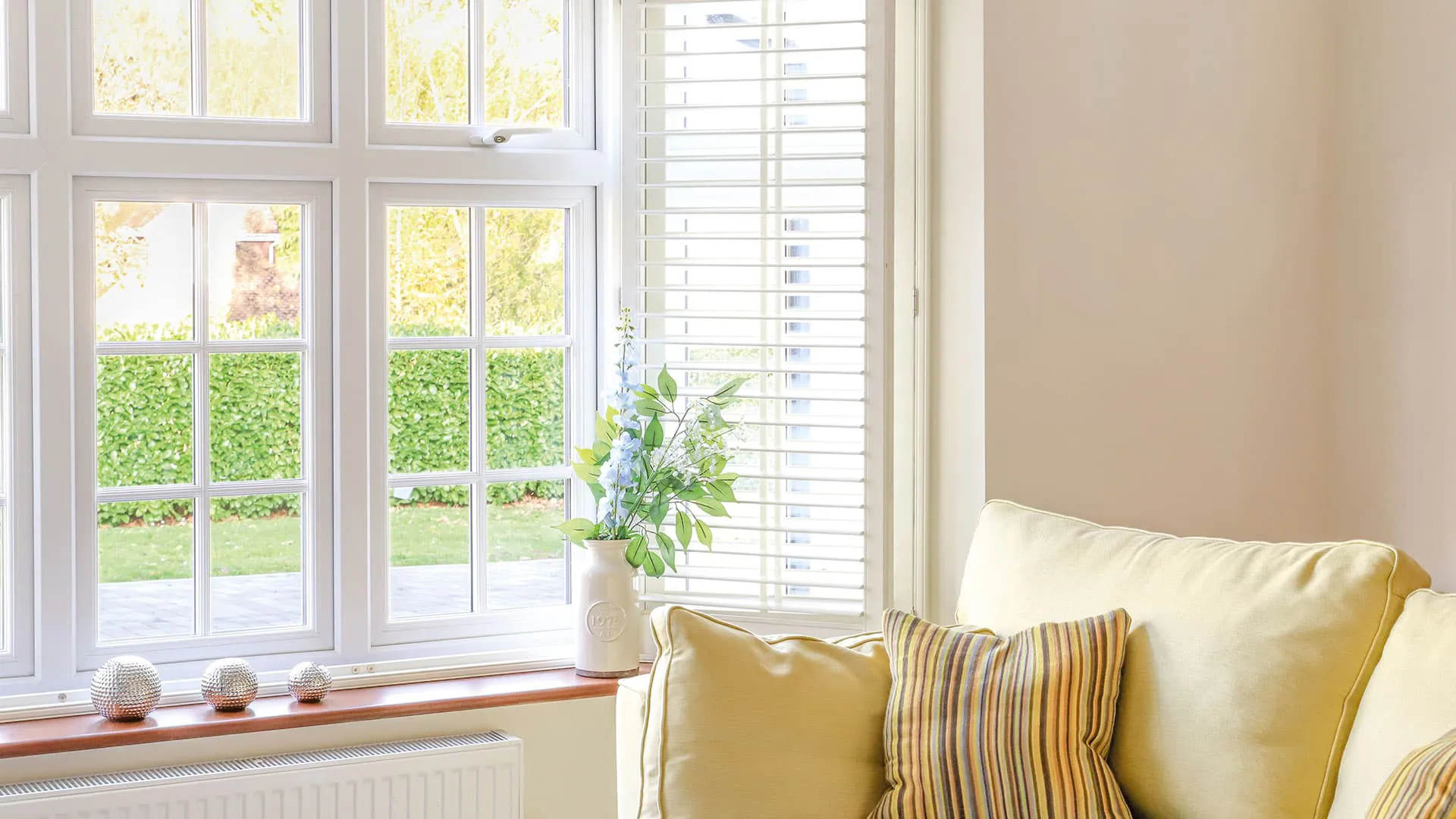 White Everest conservatory window with light yellow couch and striped cushions