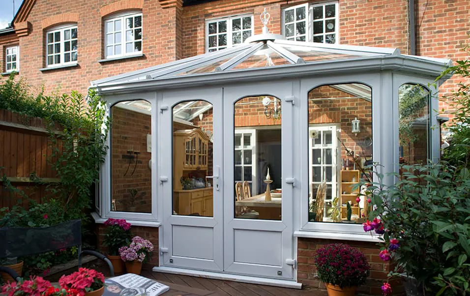 Light gray Everest conservatory with glass panels and brick house in background